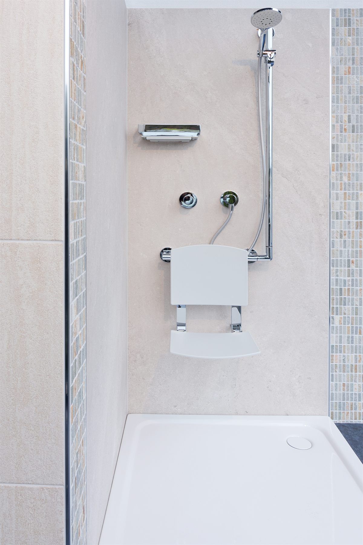 Bodengleiche Duschfläche mit hochklappbarem Duschsitz, Haltegriff und Handbrause an der Wand