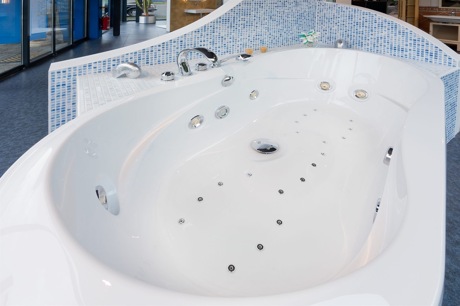 Whirlpool-Eckbadewanne mit sichtbaren Massagedüsen und Mosaikverkleidung